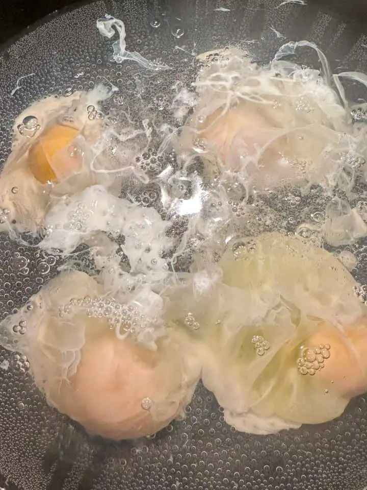 4 eggs being poached in water.