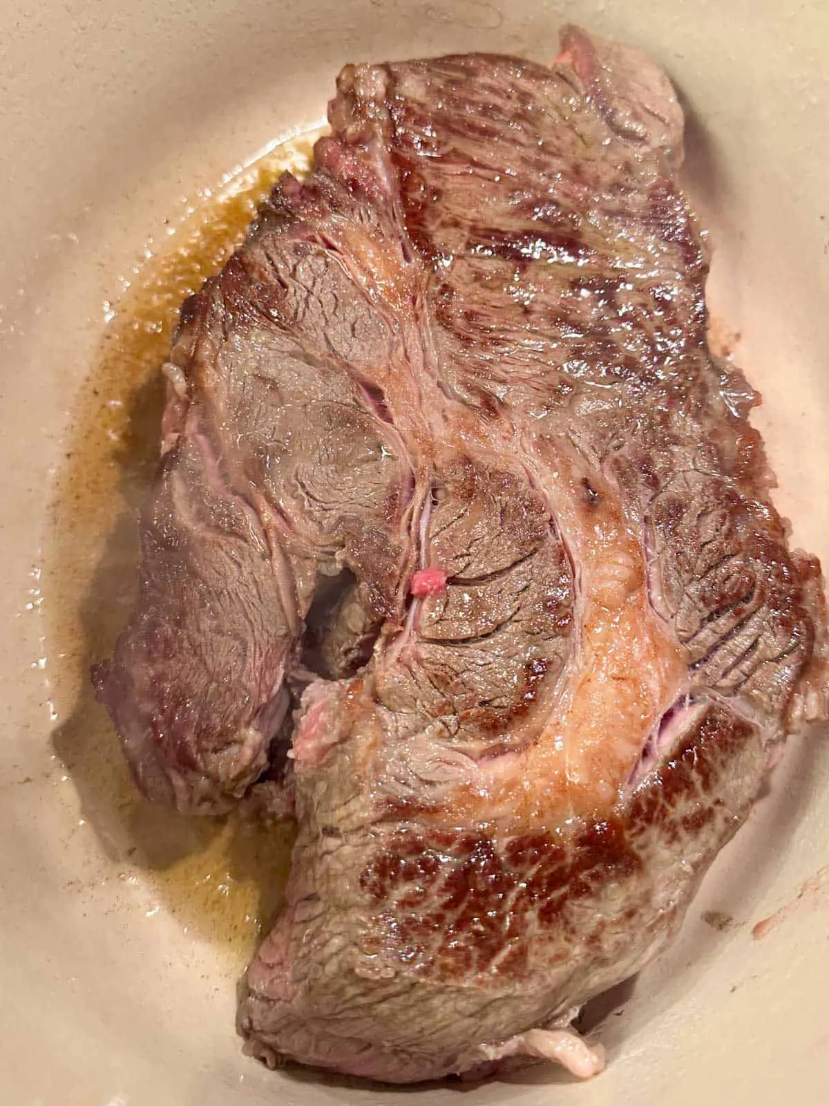 Beef chuck roast which has been browned in a Dutch oven.