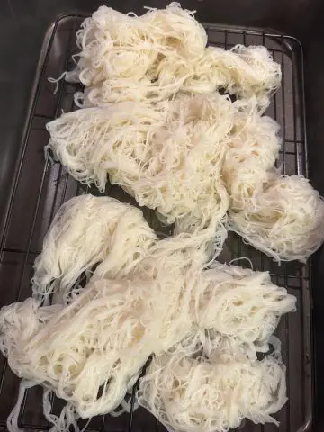 Rice vermicelli noodles spread out on a rack.