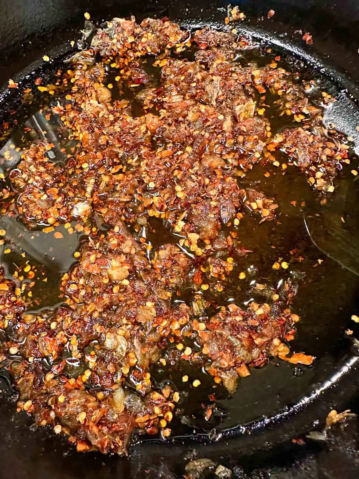 Thai chili oil with dried chilies, oil, sautéed garlic and shallots in a skillet.