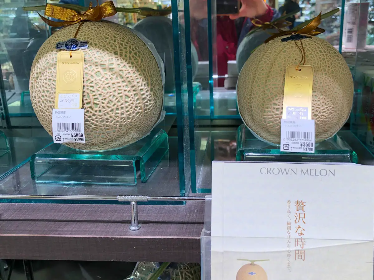 2 Crown Melons with price tags on display, and a brochure about the Crown Melon in front of the display.