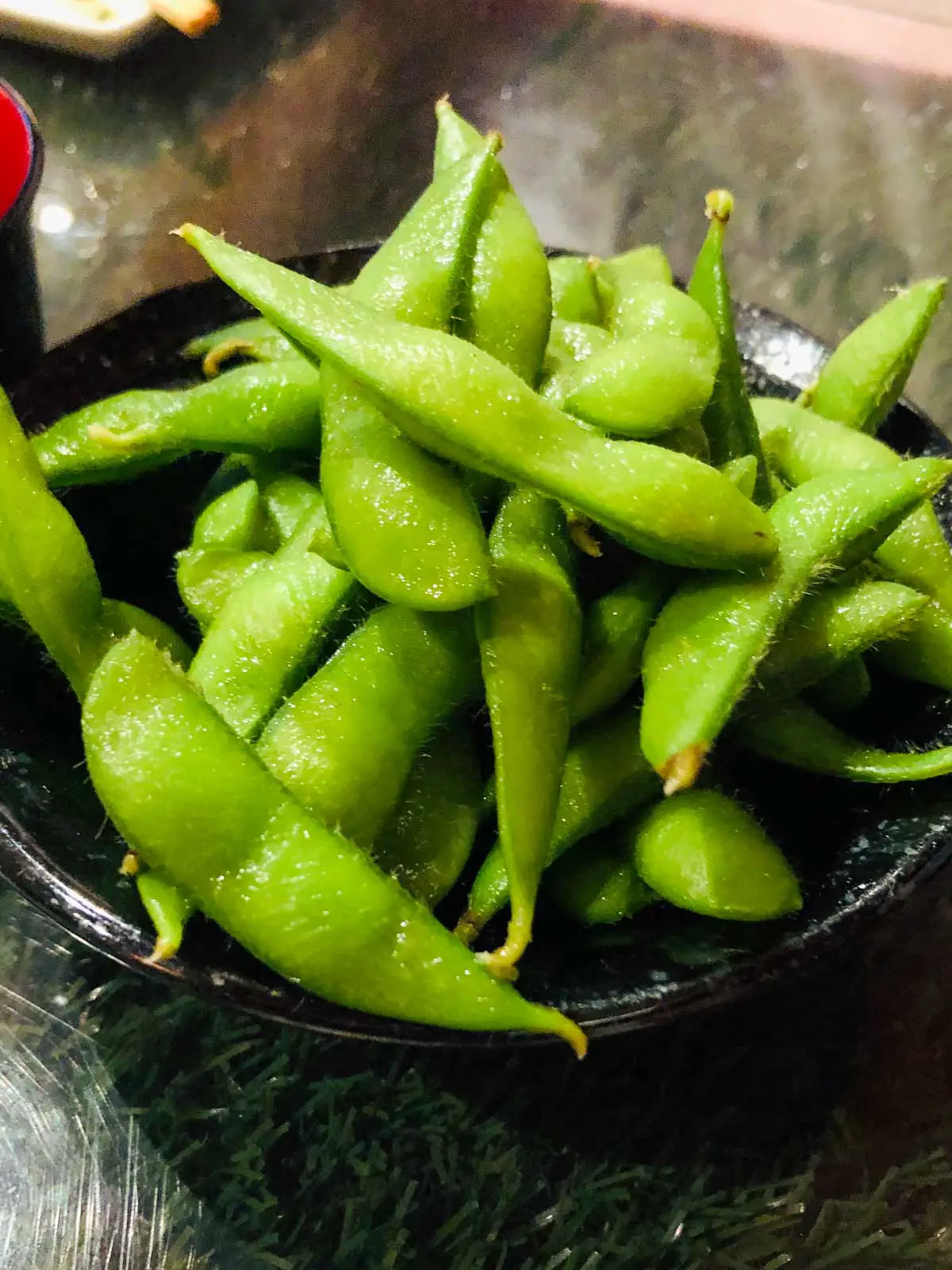 A black bowl filled with edamame pods. 