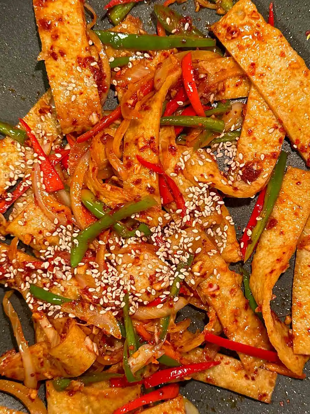 Korean fish cake that has been stir fried with onion and slivers of green and red peppers garnished with sesame seeds.