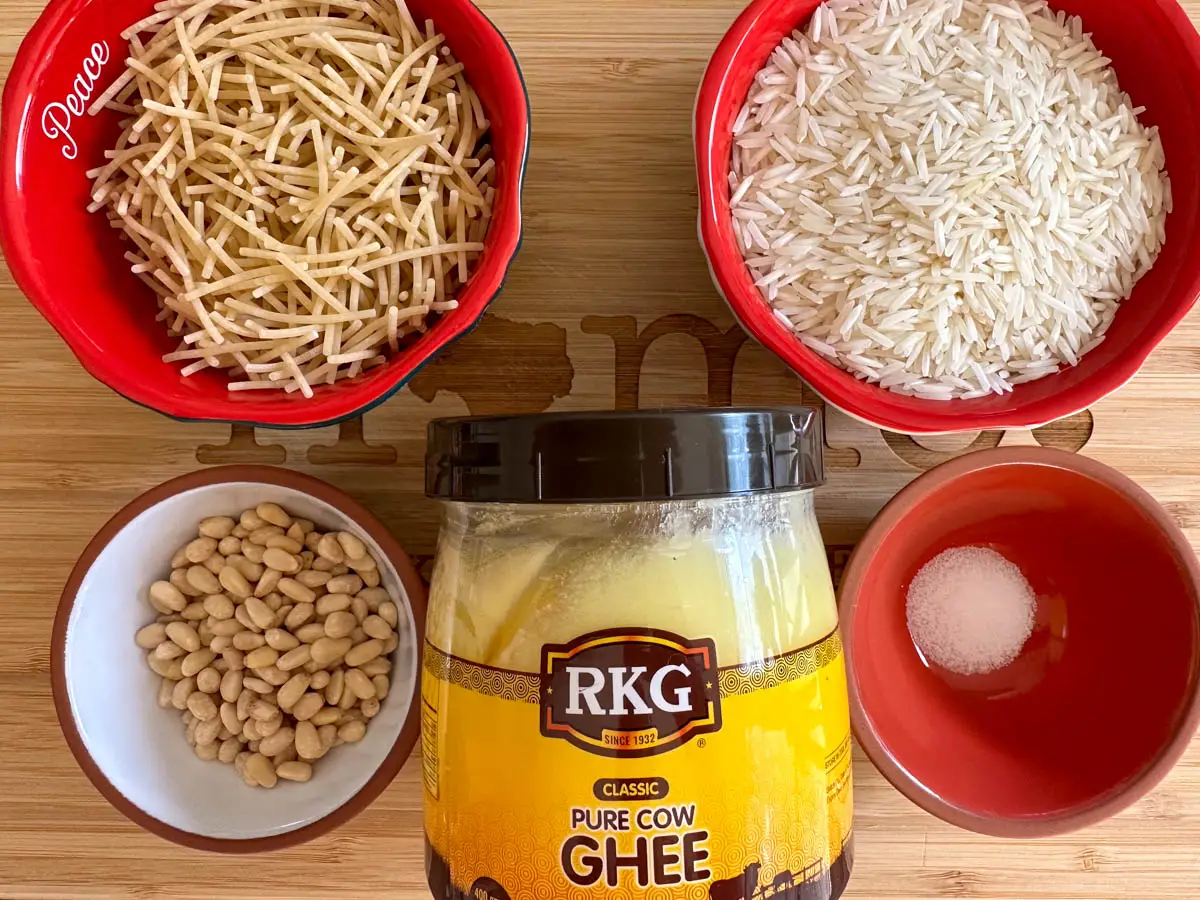 Bowls containing vermicelli pasta, basmati rice, pine nuts and salt. There is also a container of ghee.