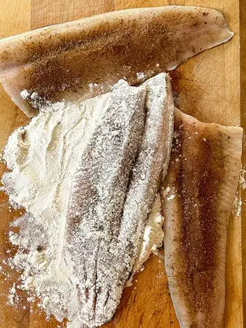 Seasoned rainbow trout fillets with one fillet coated with all purpose flour.