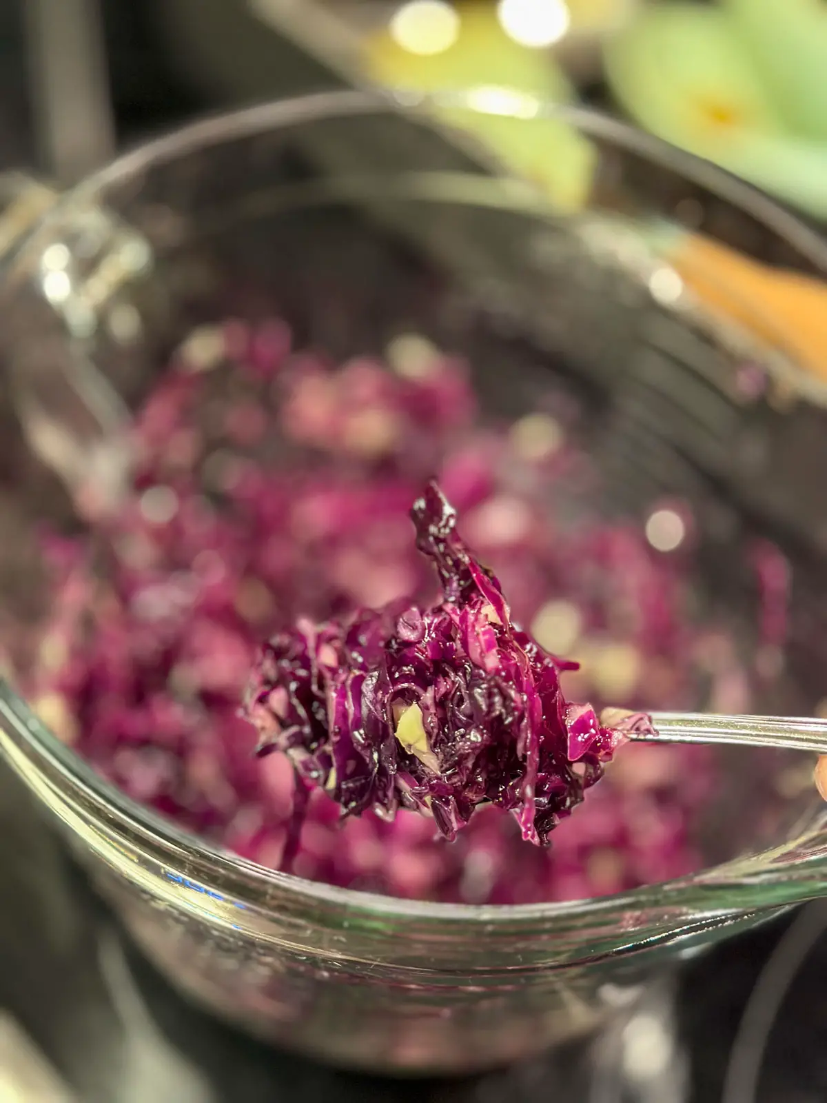 Middle Eastern Style Cabbage Salad with shredded red cabbage in a glass bowl. There is a spoon with the red cabbage in the foreground.