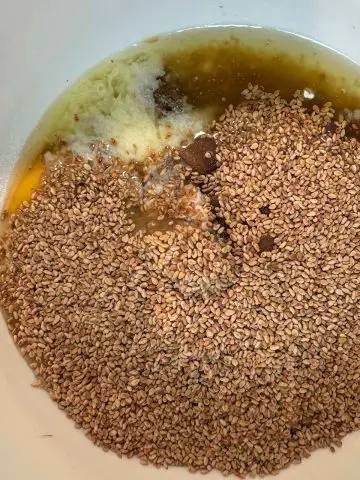 Toasted sesame seeds, an egg, melted butter, brown sugar and vanilla extract in a mixing bowl.