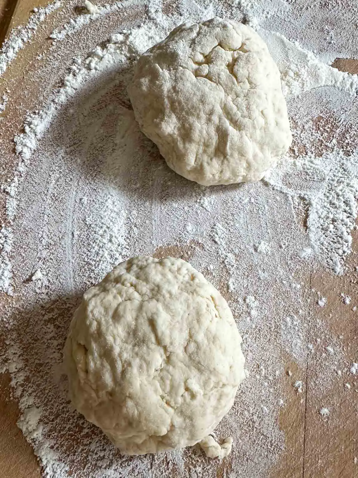 A floured cutting board with two dough balls.