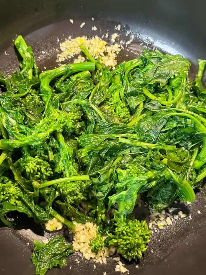 Blanched rapini, minced garlic and oil in a pan.