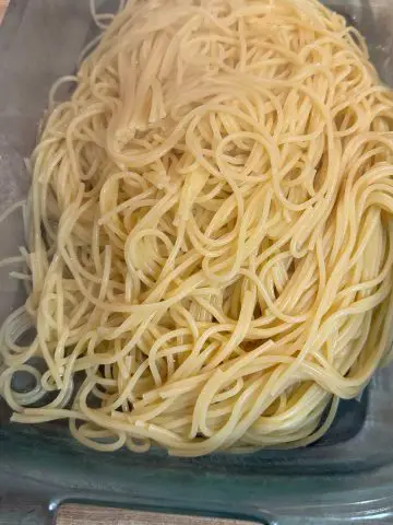 Cooked spaghetti in a glass casserole dish.