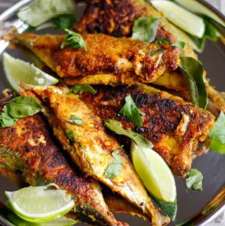 Several small mackerel which were pan fried with Indian spices and garnished with curry leaves, lime wedges, and cilantro.