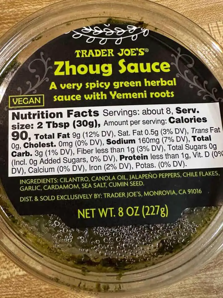 A plastic container containing Trader Joe's Zhoug sauce.