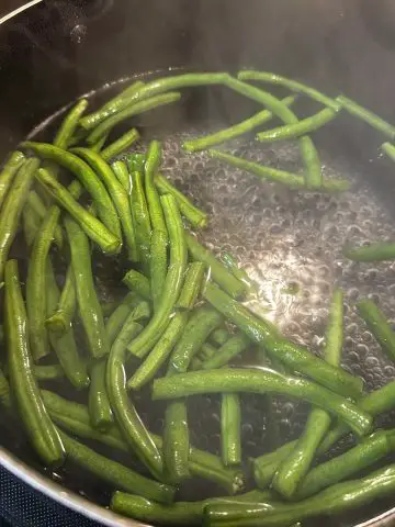 Green beans in boiling water in a large pot.