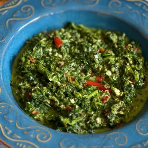 A blue bowl containing zhoug sauce which is blended cilantro with garlic, chilis, and seasonings.