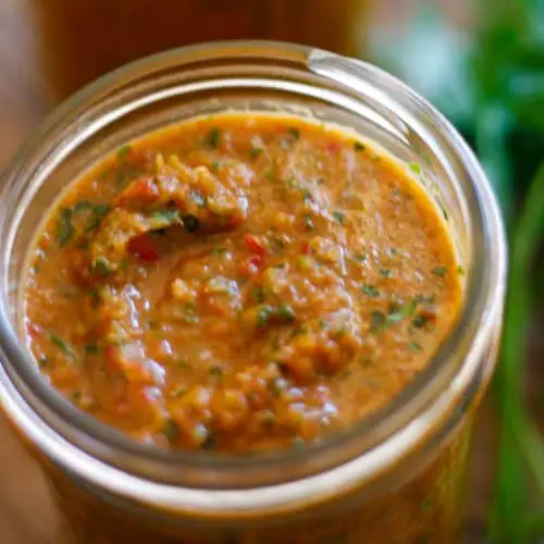A jar containing Haitian epis with parsley on the side.