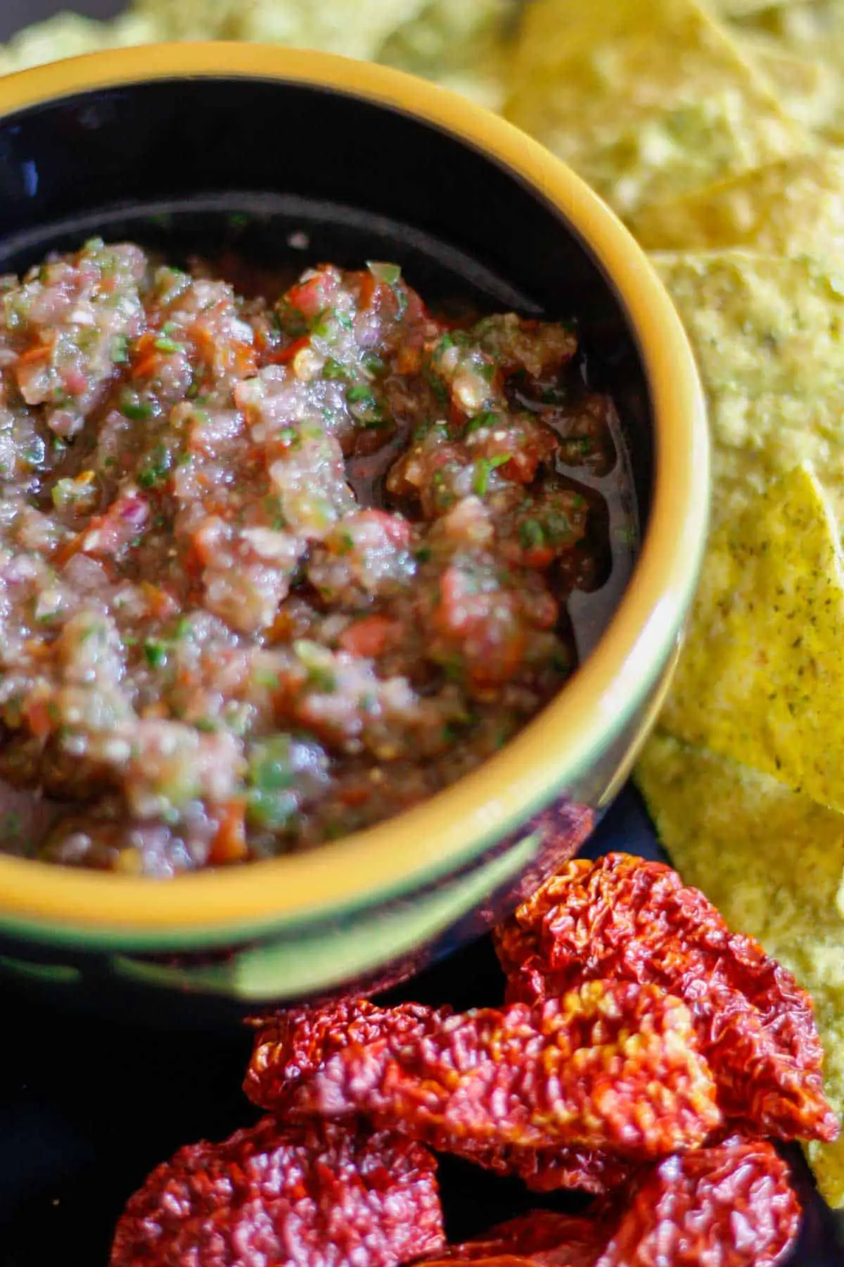 Ghost pepper salsa in a bowl surrounded by tortilla chips and dried Ghost chilies.