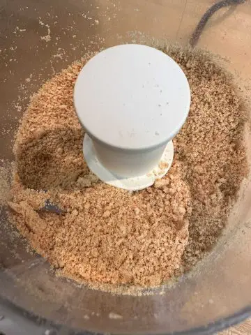 A food processor containing crushed graham crackers.