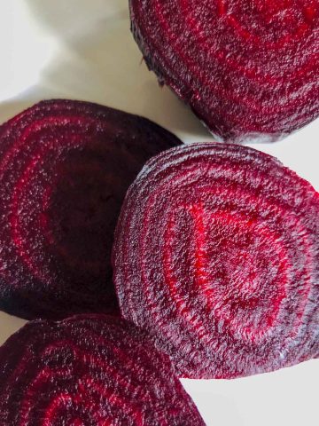 Red beets that have been cut in half so that you can see striations in the beets.