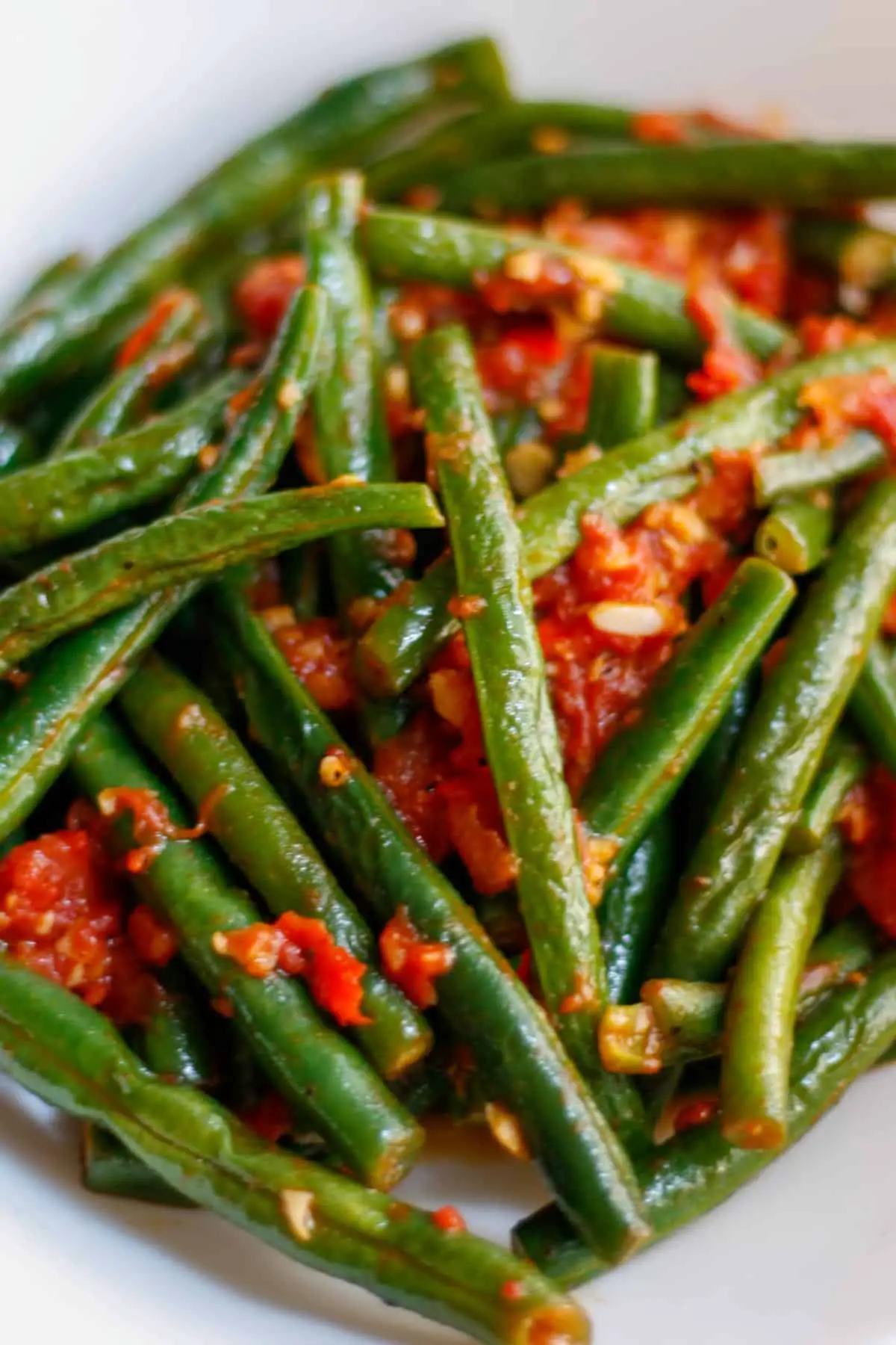 Green beans and tomatoes in a white dish.