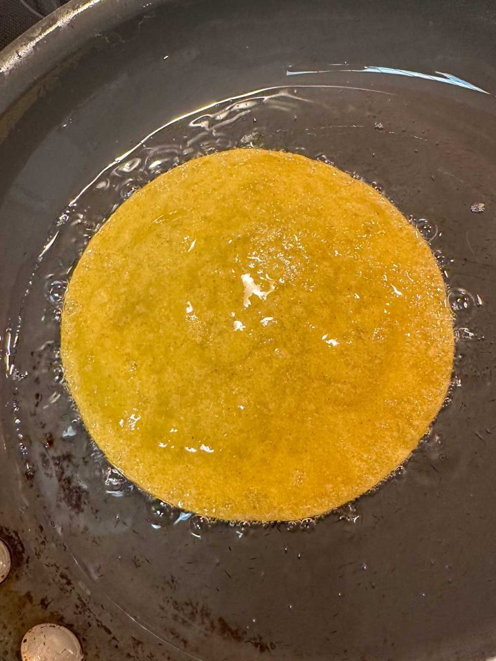 A corn tortilla frying in lard.