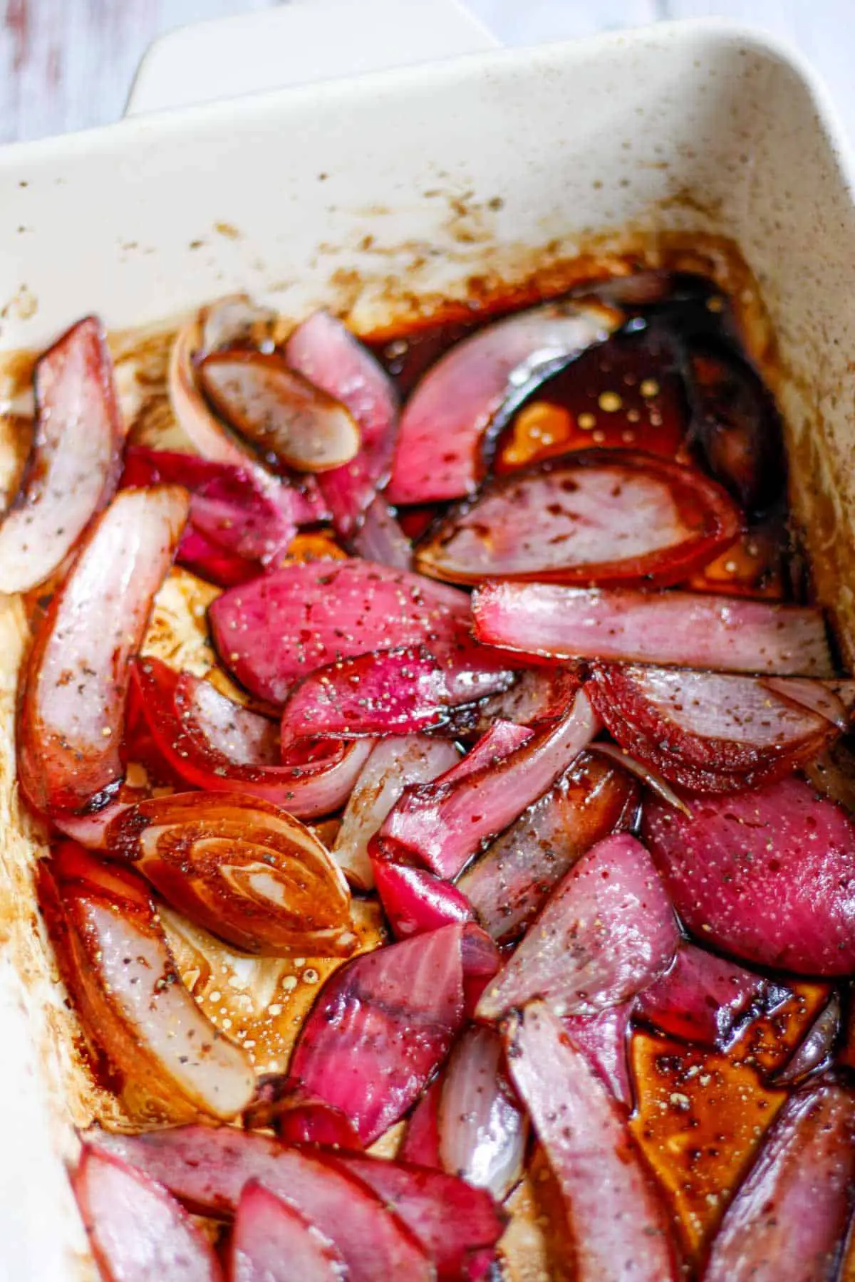 Red onion slices that have been roasted with balsamic vinegar in a baking dish.