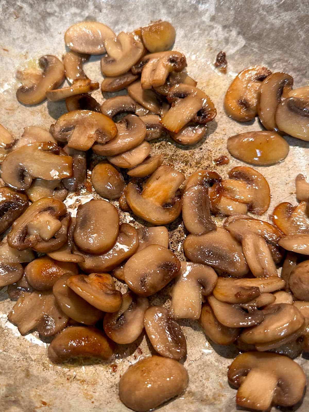 Cooked sliced mushrooms in a skillet.