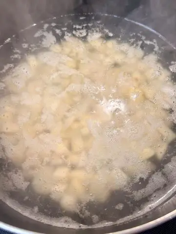 Potato cut into bite sized pieces covered with water in a large pot.