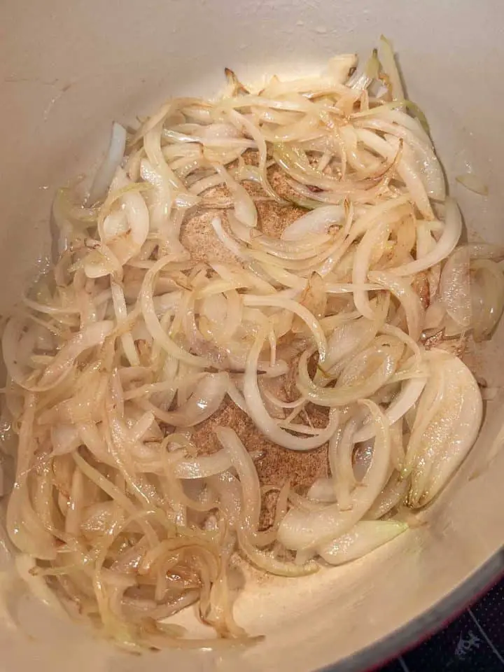 Sliced onions being browned in a Dutch oven.
