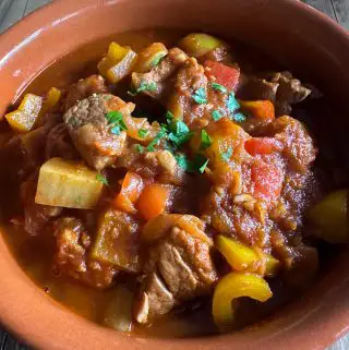 Hungarian Pork Goulash garnished with parsley in a terracotta bowl.