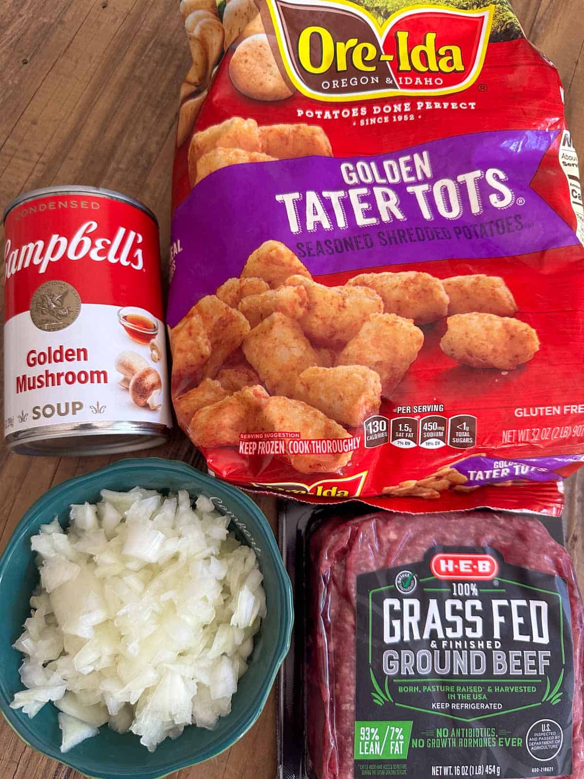 A package of Ore-Ida Golden Tater Tots, a can of Campbell's Golden Mushroom Soup, a bowl with diced onion, and a package of grass fed ground beef.