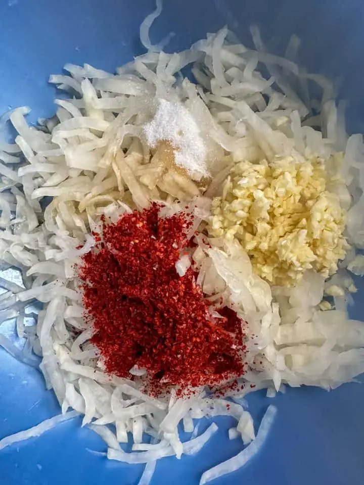 Julienned daikon radish, garlic, and gochugaru in a blue bowl.