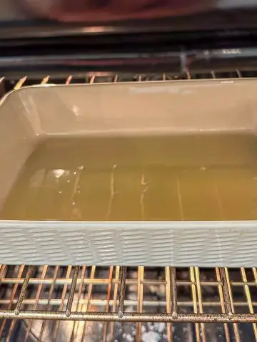 A dish containing chicken fat heating in an oven.