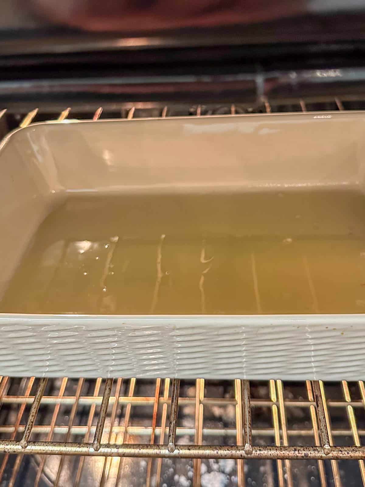 A dish containing chicken fat heating in an oven.