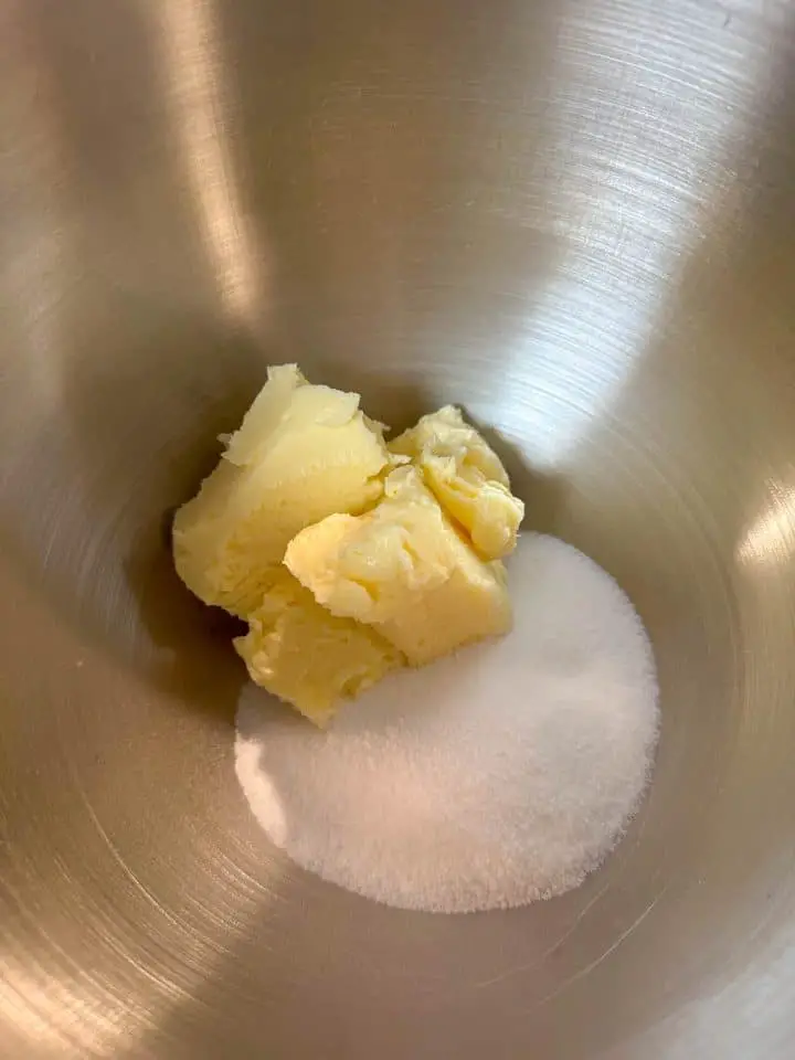 A stainless steel mixing bowl with softened butter and sugar.