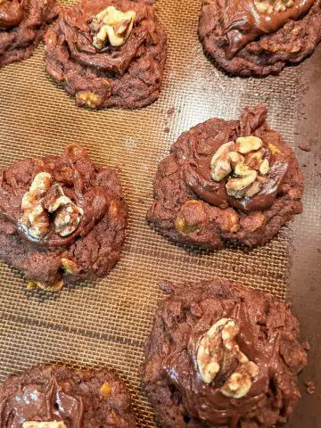 Easy New Zealand Afghan Cornflake Cookies on a silicone baking mat. The cookies are topped with a half walnut.