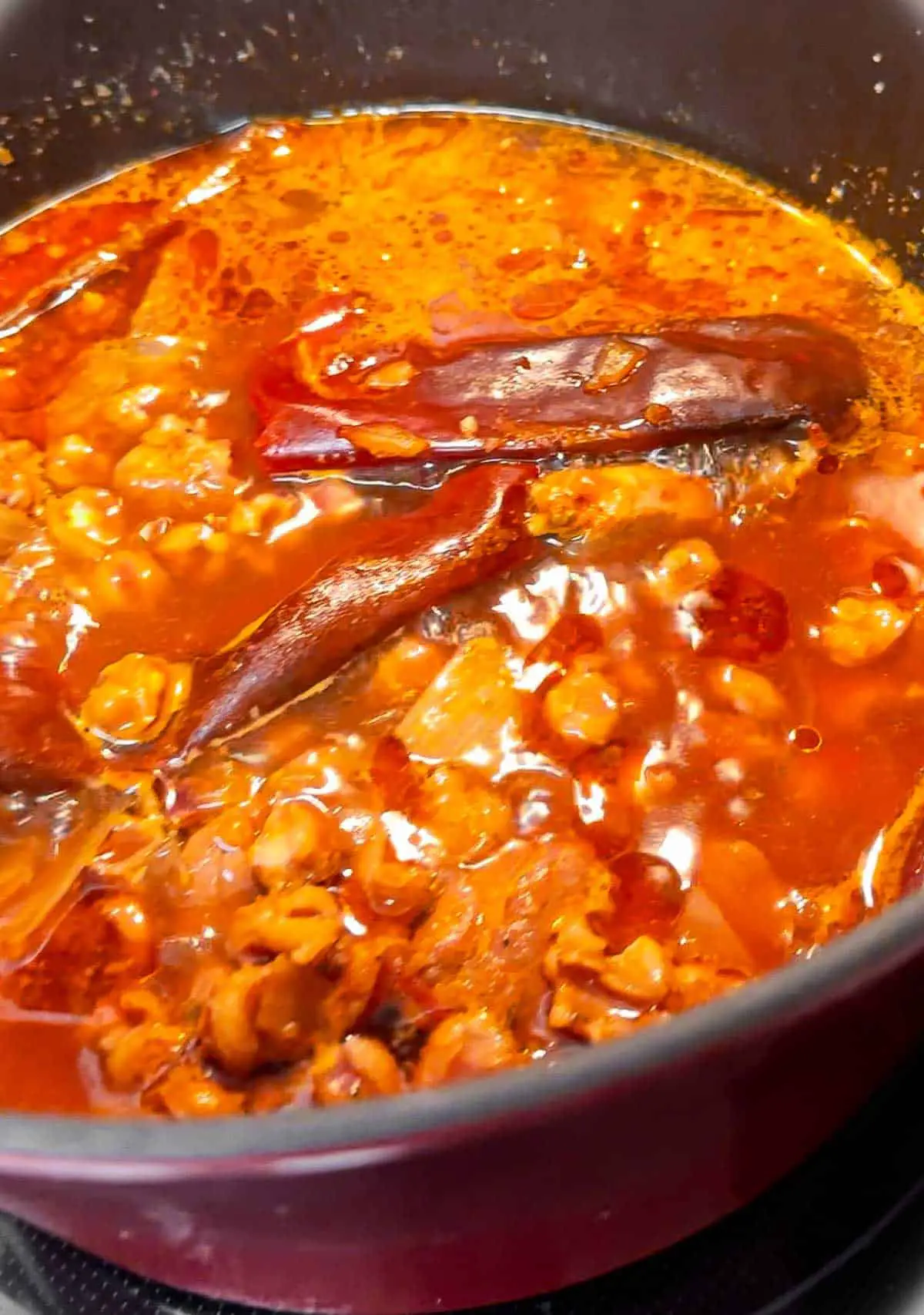 A large pot containing pork posole in a seasoned broth with red chiles.