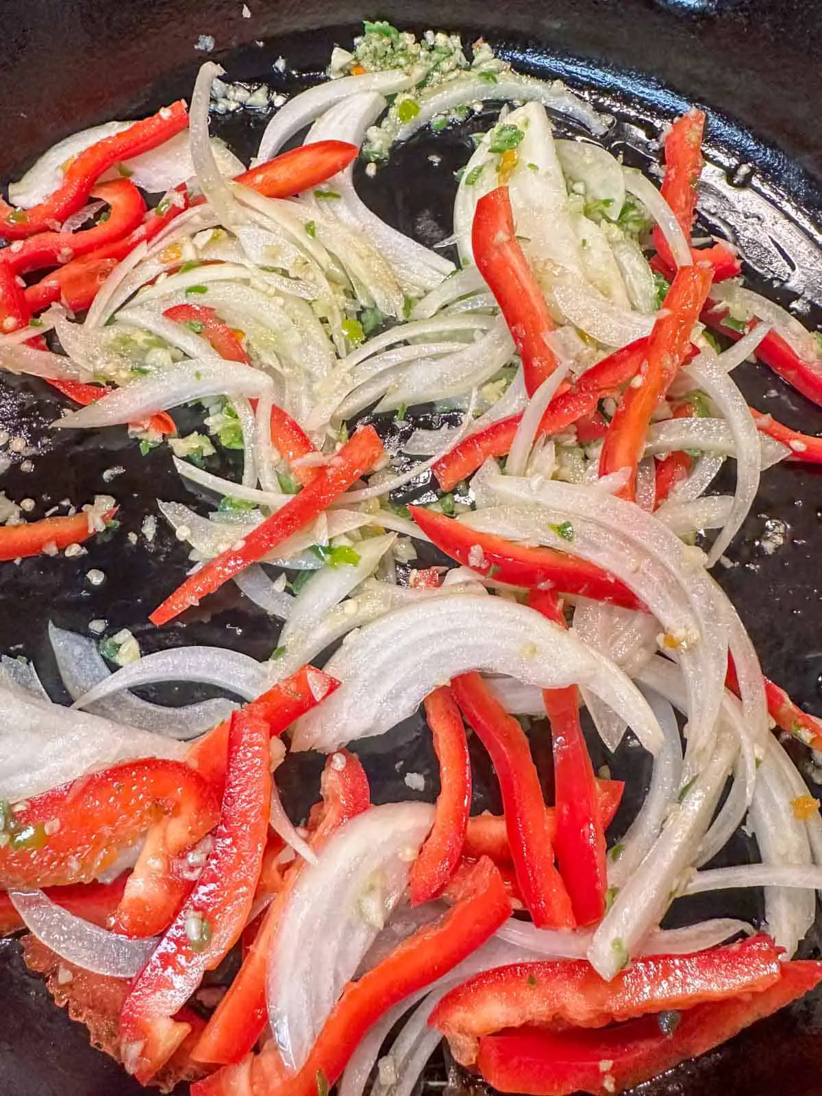 Sliced red bell pepper and onion with minced garlic and minced Thai chilis.