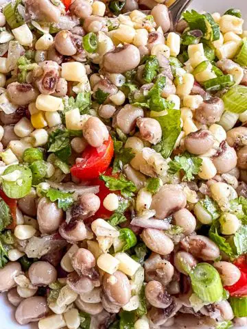 Texas caviar which is a mixture of shoepeg corn, black eyed peas, green onions, cilantro, grape tomatoes, and minced garlic, onion, and jalapeno pepper.
