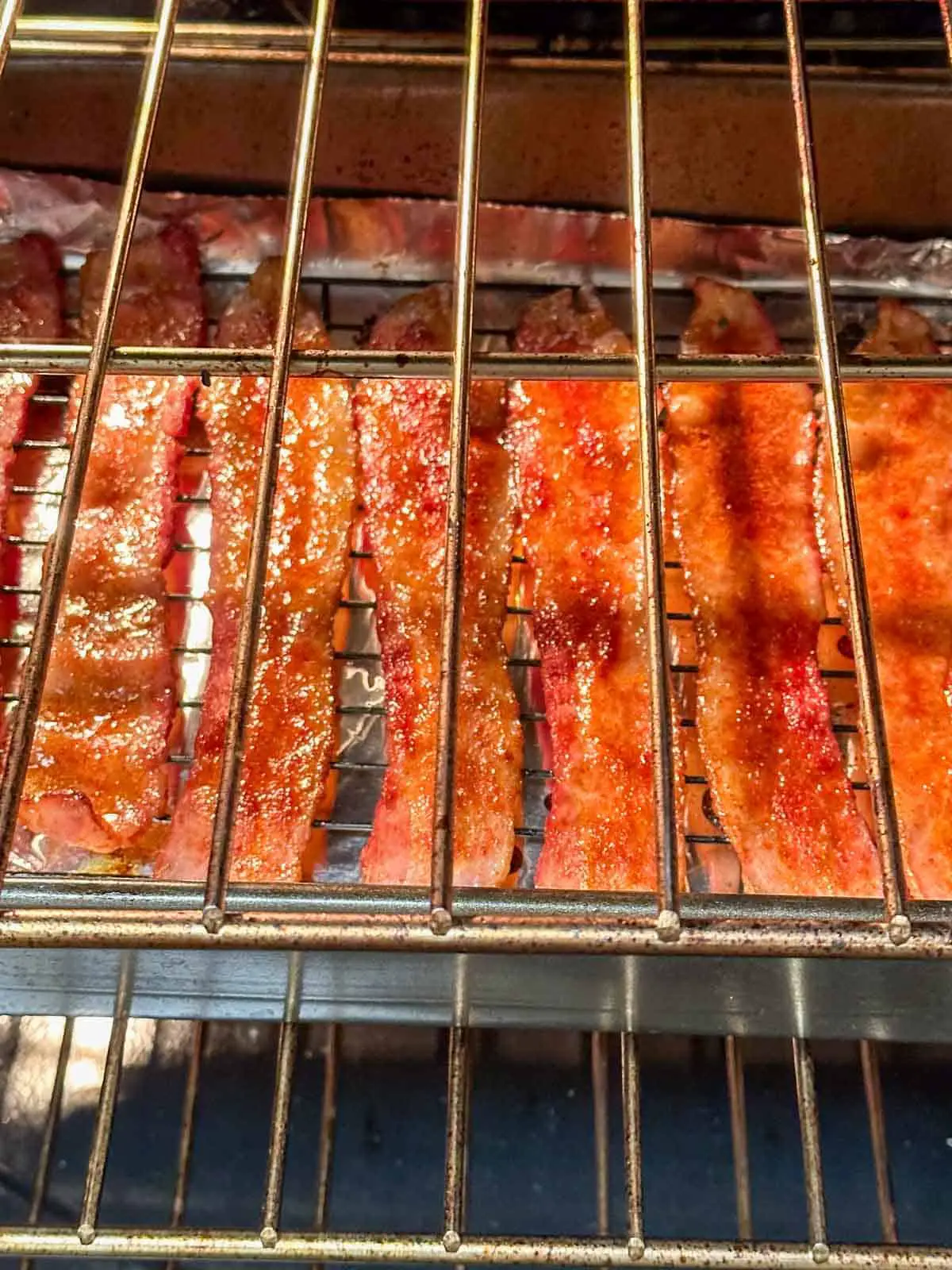 Scorpion pepper bacon on a roasting tray rack baking in an oven.