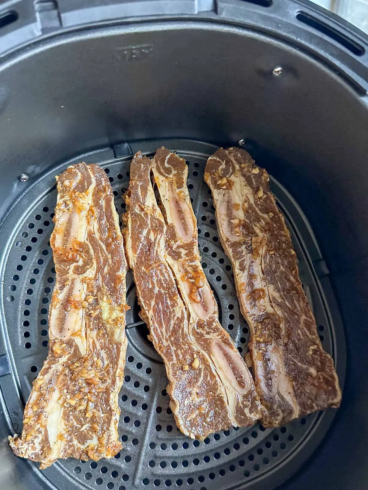 Marinated Korean beef short ribs in an air fryer basket.
