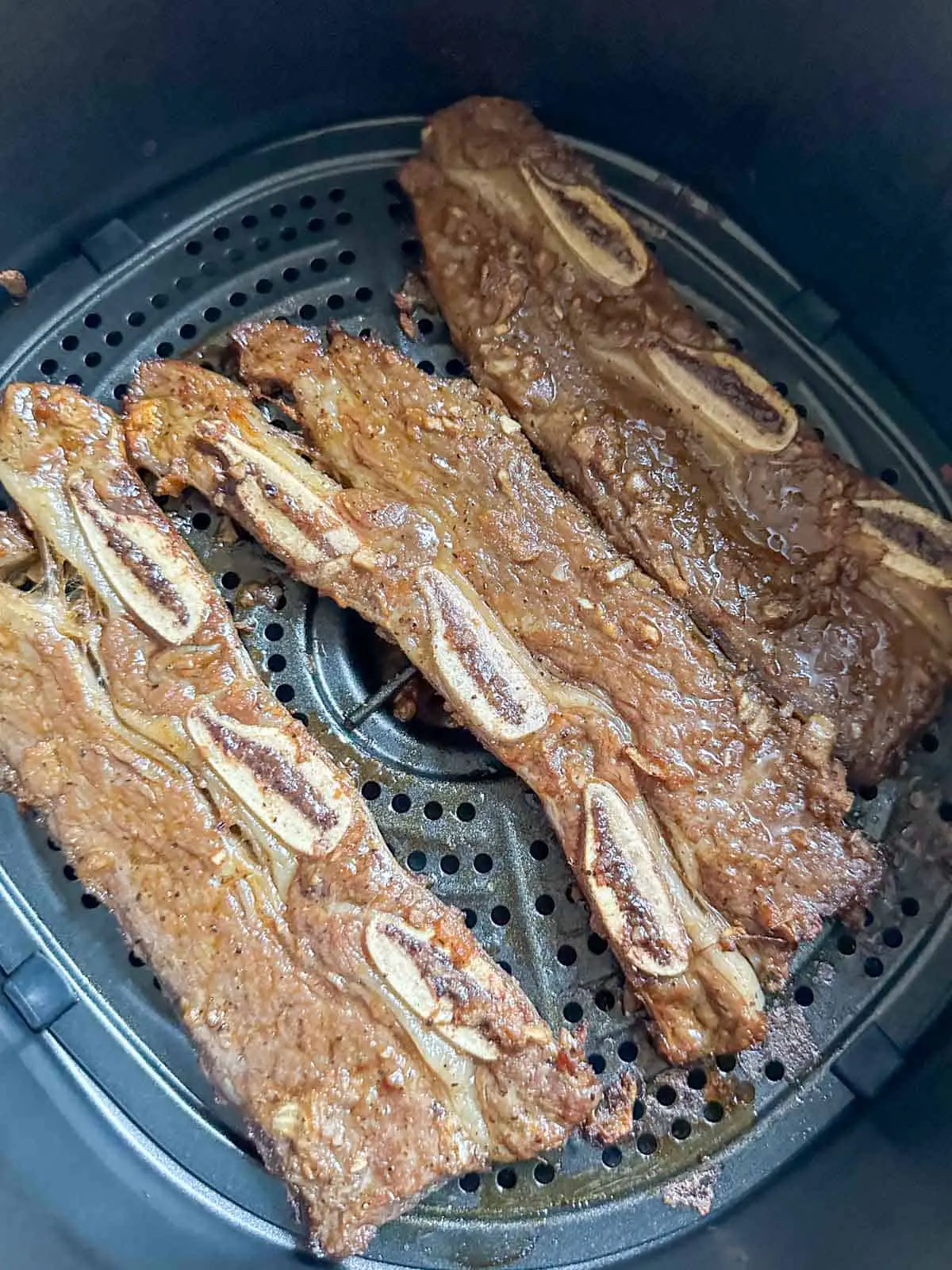 Cooked Korean short ribs in an air fryer basket.