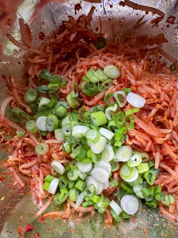 Korean spicy bean sprouts and lots of sliced green onions in a mixing bowl.