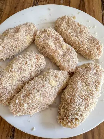 Ground chicken cutlets covered in panko displayed on a white plate.