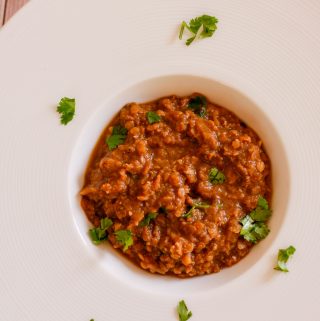 Ethiopian red split lentil wat in a white dish garnished with cilantro.