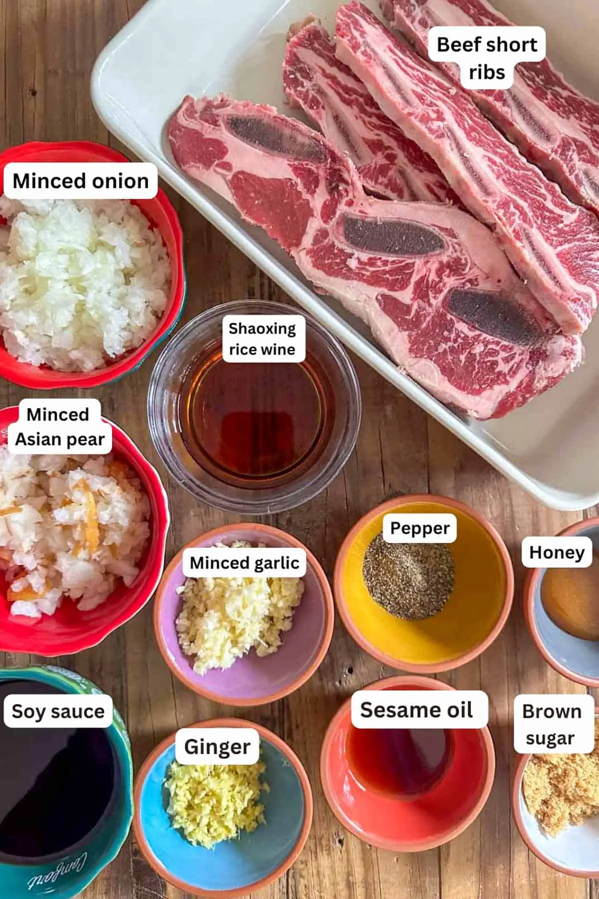 Ingredients for Air Fryer Korean Galbi Short Ribs including beef short ribs, minced onion, minced Asian pear, Shaoxing rice wine, minced garlic, pepper, honey, soy sauce, ginger, sesame oil, and brown sugar.
