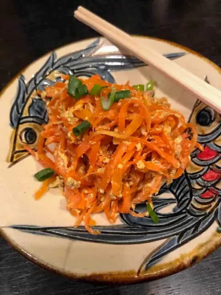 Japanese Okinawan Carrot Recipe With Tuna and Egg on a plate with fish patterns and a pair of chopsticks.