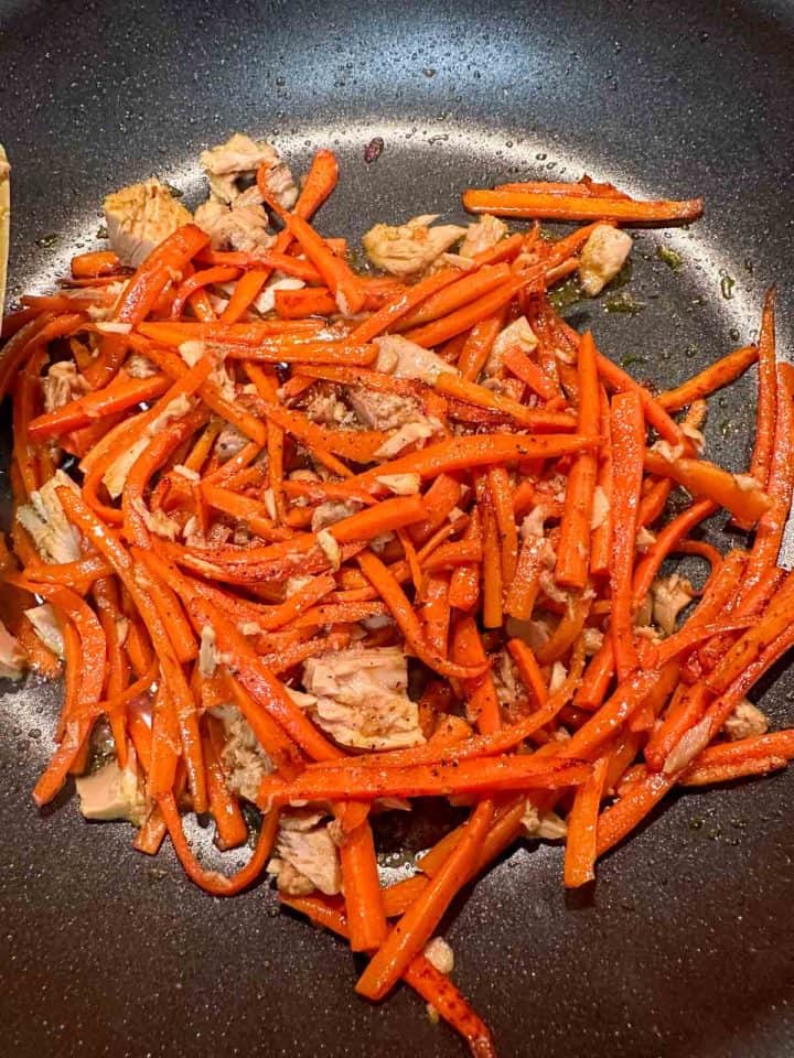 Julienned carrots with tuna and seasonings in a skillet.