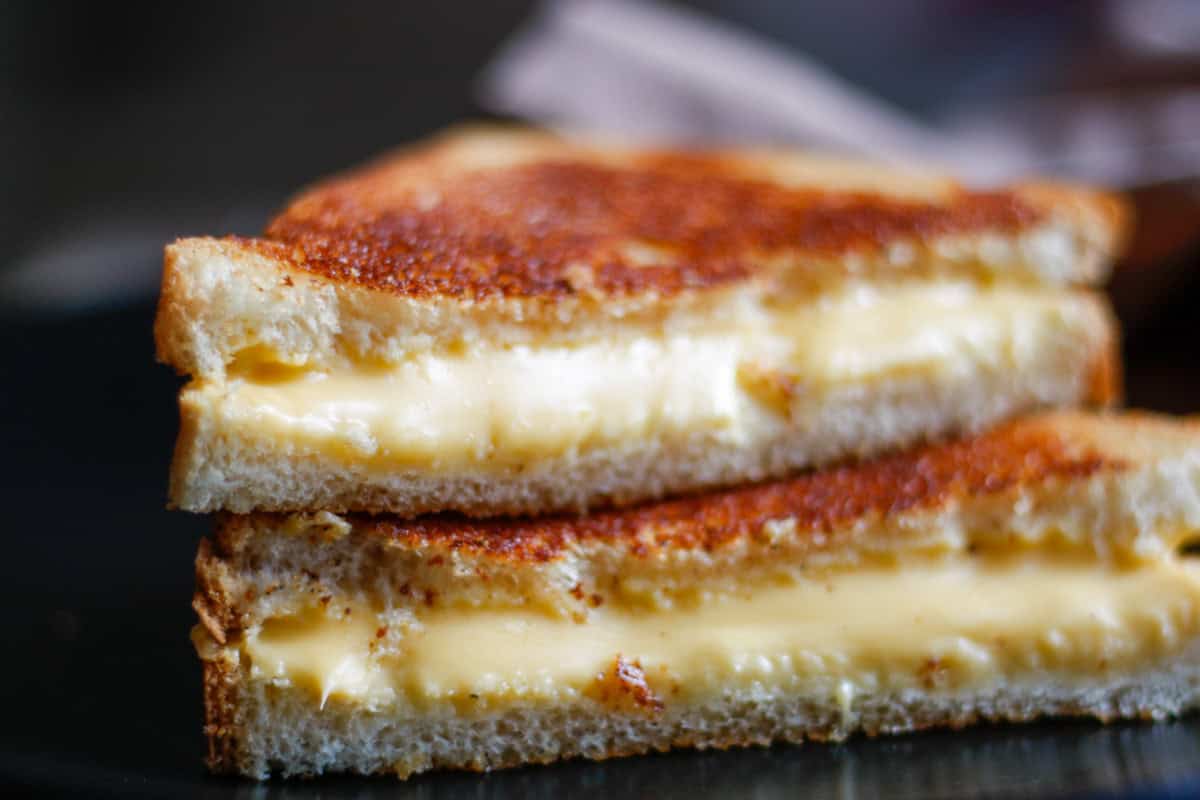 A classic grilled cheese sandwich cut in half with the halves stacked on top of each other.