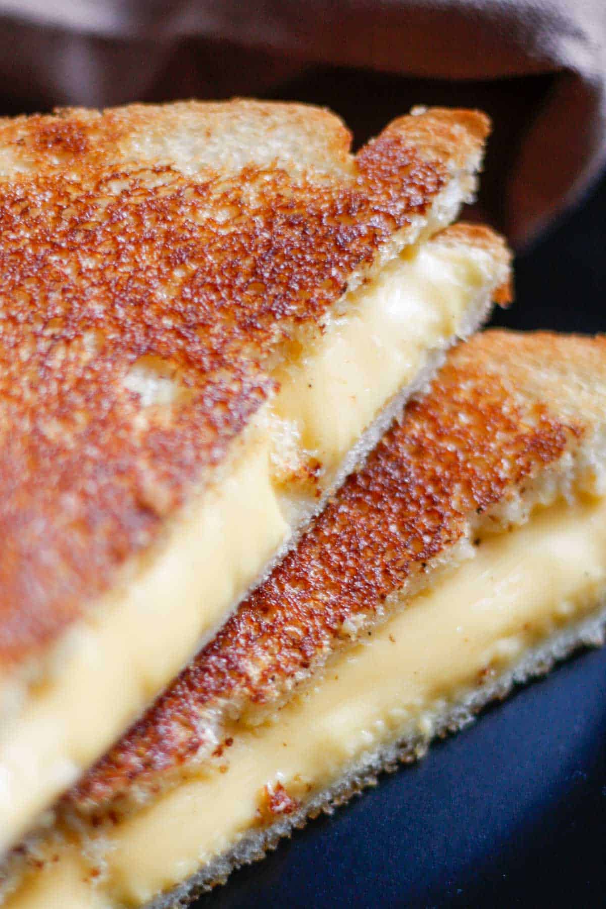 A classic grilled cheese sandwich cut in half with the halves stacked on top of each other.