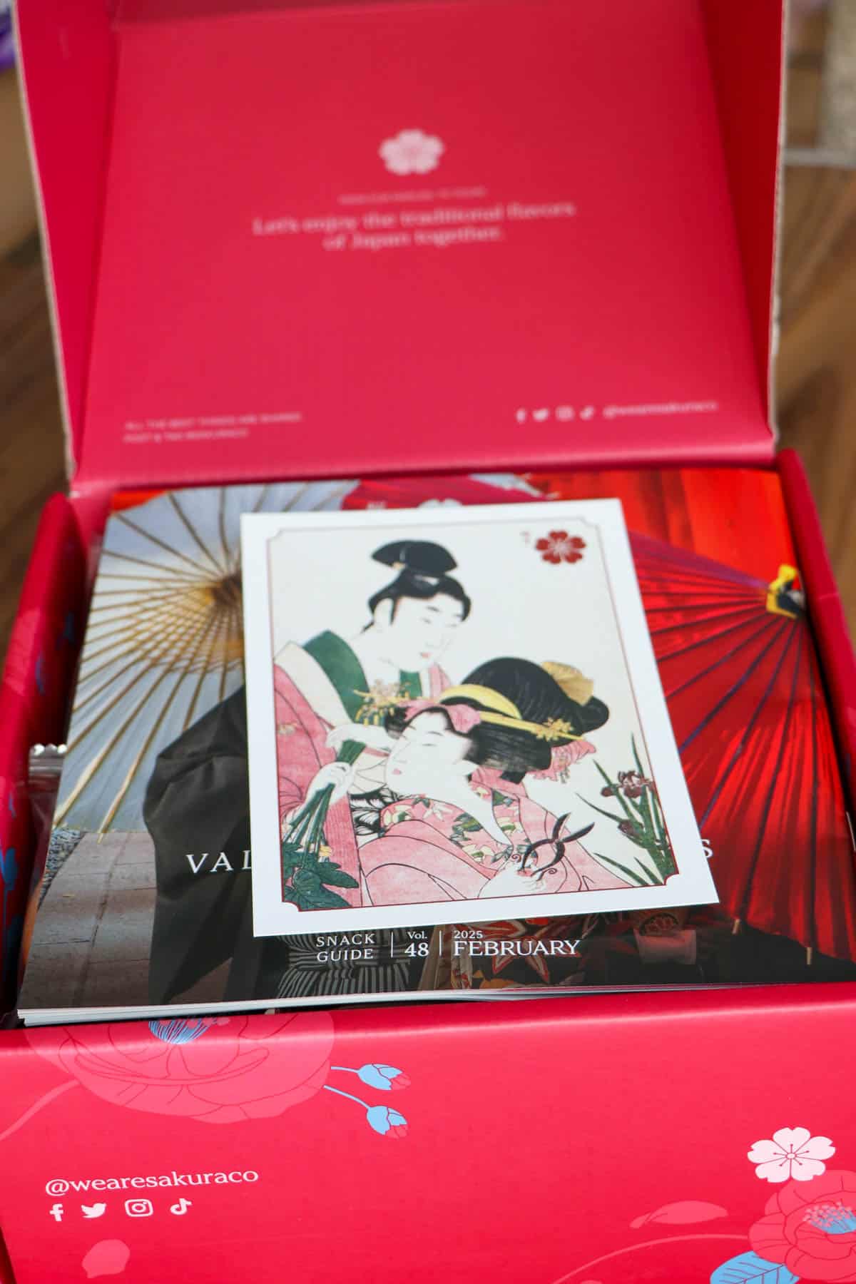 A Valentine's themed Sakuraco box opened to show a Japanese style postcard on top of the contents in the box.